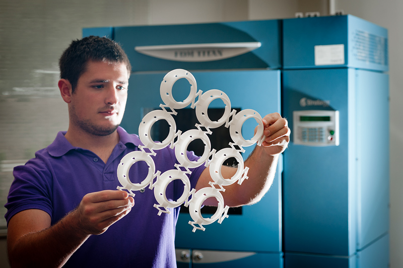 Student inspecting a 3D printed machinery part