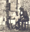 Kephart sitting at table in camp.